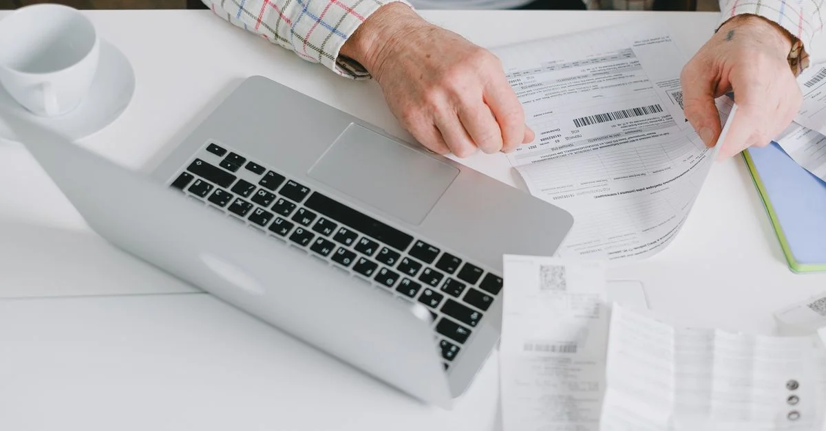 Gros plan sur des mains organisant des documents sur un bureau avec un ordinateur portable.