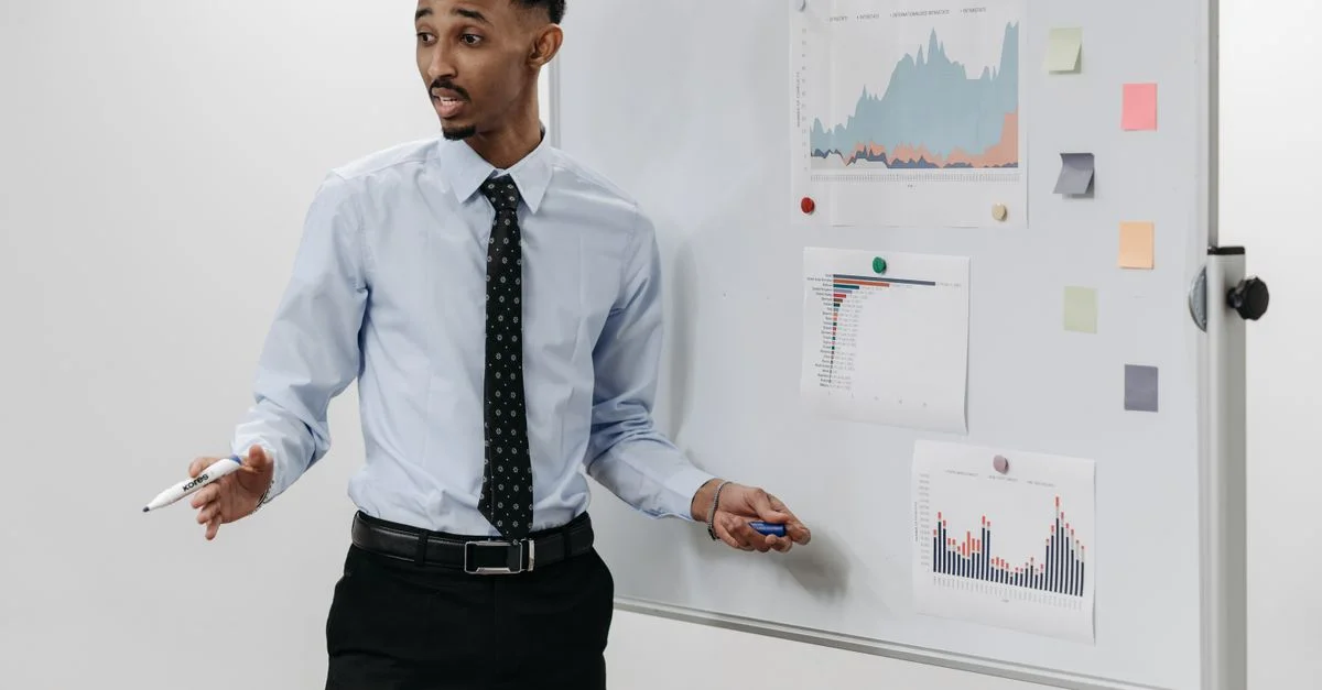 Homme présentant une présentation d'affaires avec des graphiques sur un tableau blanc.