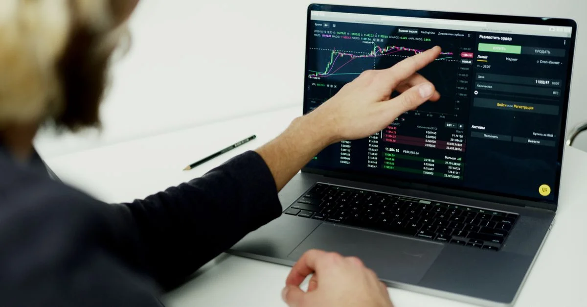 Une personne analysant des graphiques du marché boursier sur un écran d'ordinateur portable, présentant des perspectives de trading.