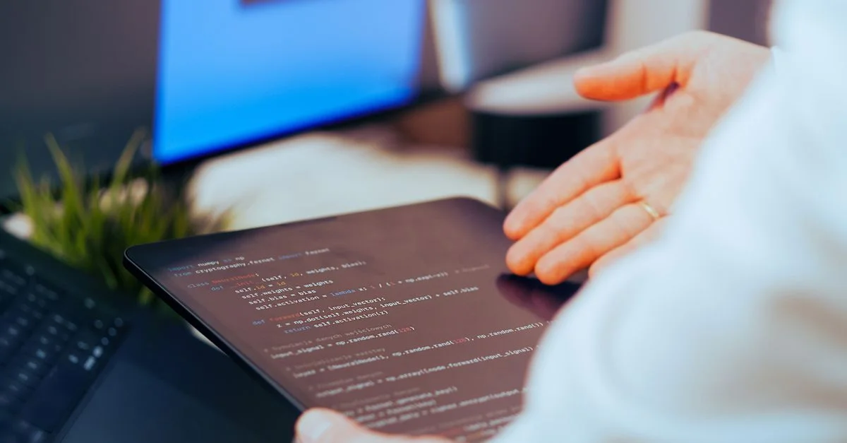 Un développeur de logiciels analyse du code sur une tablette dans un espace de travail de bureau moderne.
